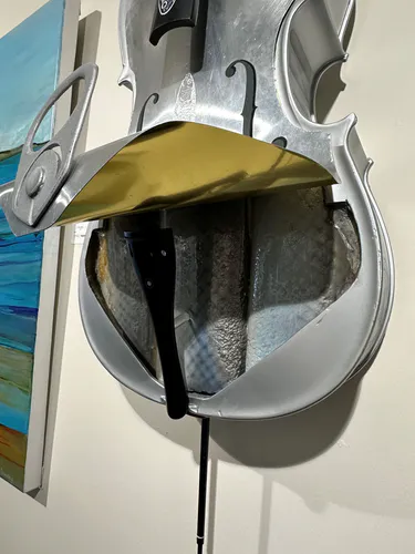 An in-situ contemporary sculpture of a metal Cello with an open Sardine can base by New Zealand artist Bruce Rule, available at The Little Gallery Whangamata